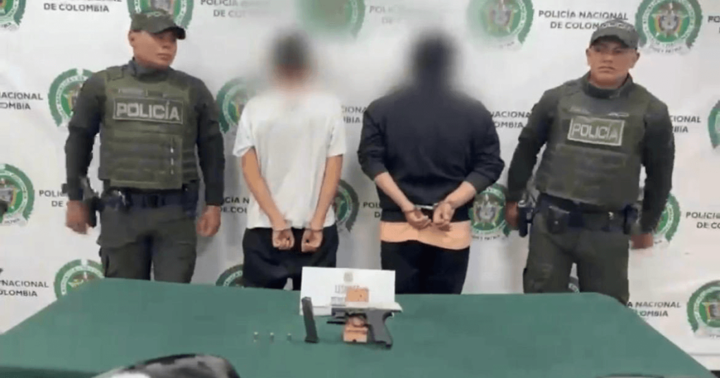 Dos hombres capturados, en medio de dos policías.