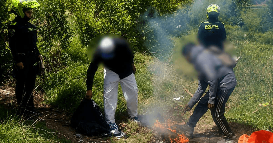 Foto que muestra dos policías y dos personas apagando una fogata 