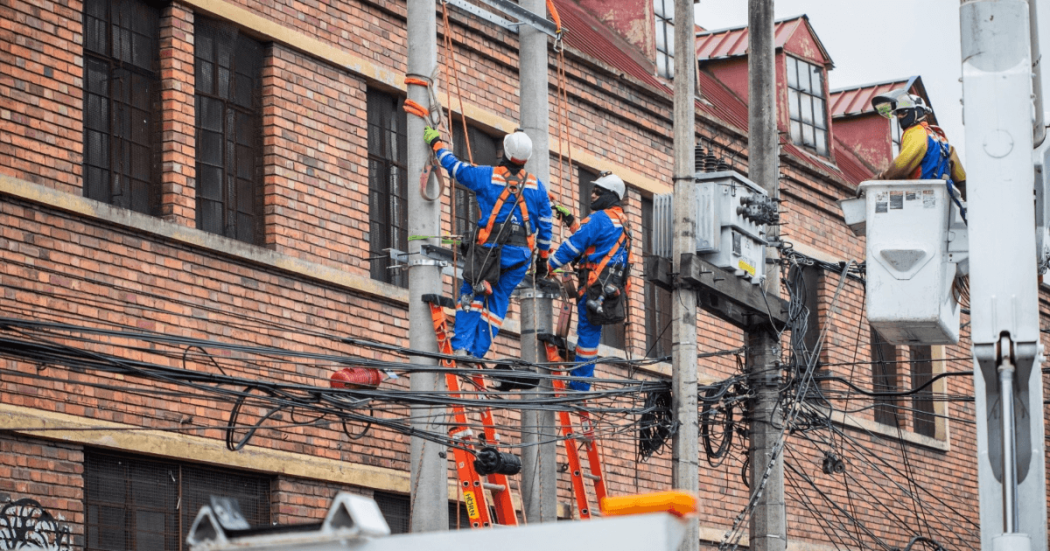 Foto que muestra dos personas con uniforme de Enel Colombia en un poste de luz