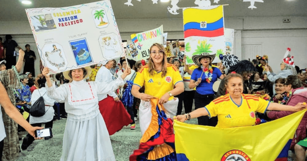 Foto que muestra personas mayores bailando con banderas de Colombia