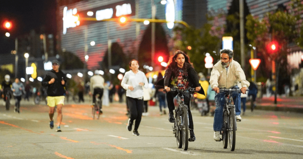 Personas en bicicleta, corriendo y caminando durante una jornada nocturna de actividad física en una vía de Bogotá.