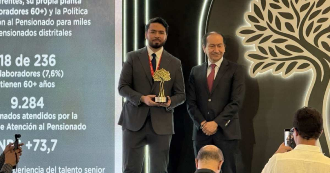 Foto que muestra dos personas sonriendo con un premio en la mano