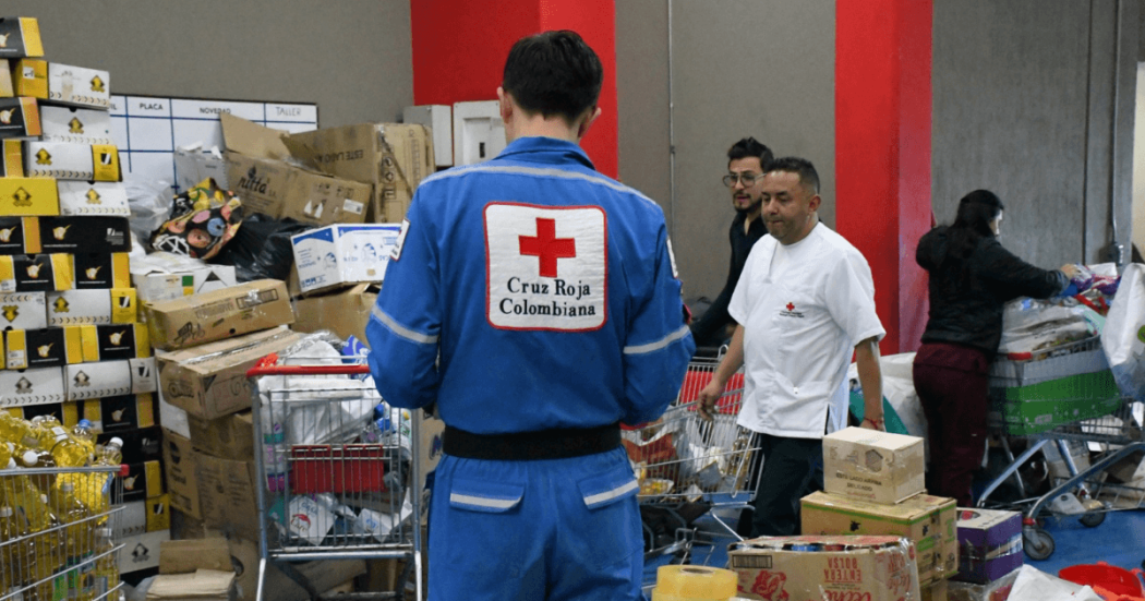Personal de la Cruz Roja Colombiana organiza y clasifica donaciones en un centro de acopio con cajas, mercados, elementos de ayuda humanitaria y carritos de transporte en Bogotá.
