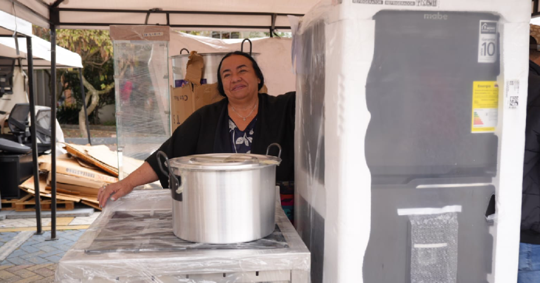 Mujer con una nevera y una olla, para apoyo a su emprendimiento en Bogotá.