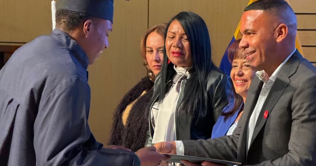 Un joven recibiendo su diploma de bachiller durante ceremonia en Bogotá.
