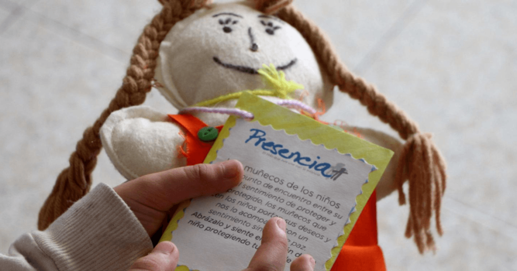 Manos de niña sosteniendo una muñeca de trapo.