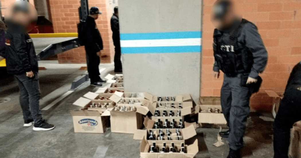 Foto que muestra cajas con licor en el piso y personal de la Fiscalía 