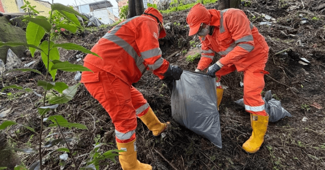 Foto que muestra dos personas con el uniforme de Aguas Bogotá levantando residuos de la calle