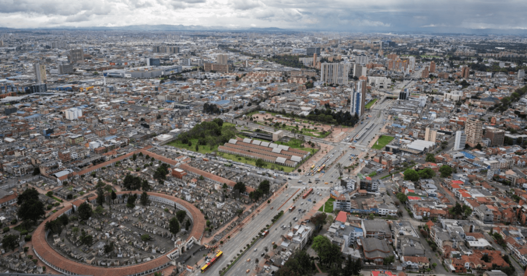 Vista aérea de Bogotá con alta densidad de edificaciones, una importante avenida en primer plano, el Cementerio Central visible en la parte inferior izquierda.