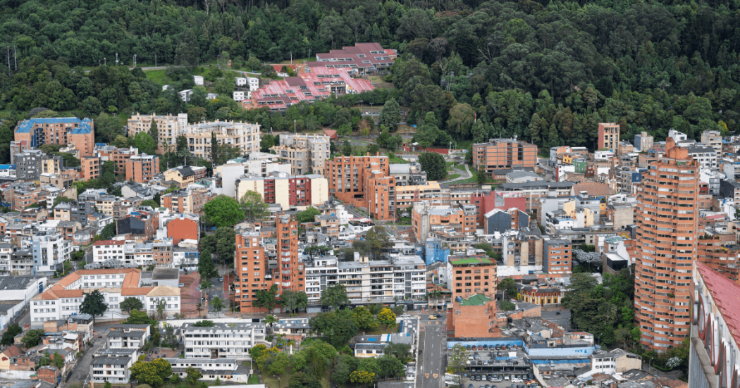 Vista panorámica de Bogotá con edificios residenciales y comerciales de diferentes alturas en primer plano.