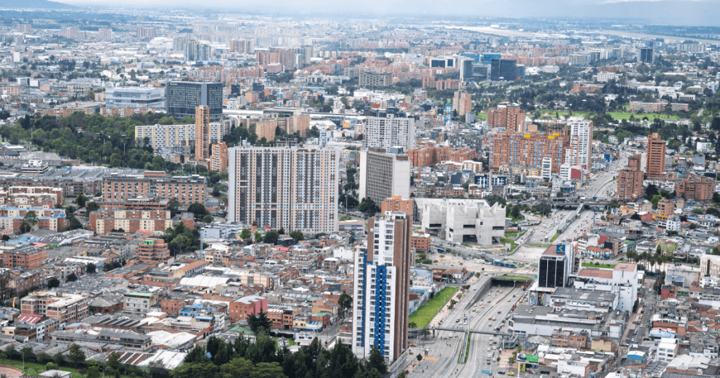Vista panorámica de Bogotá con edificios residenciales, vías principales, zonas comerciales y amplias áreas urbanas bajo un cielo nublado.
