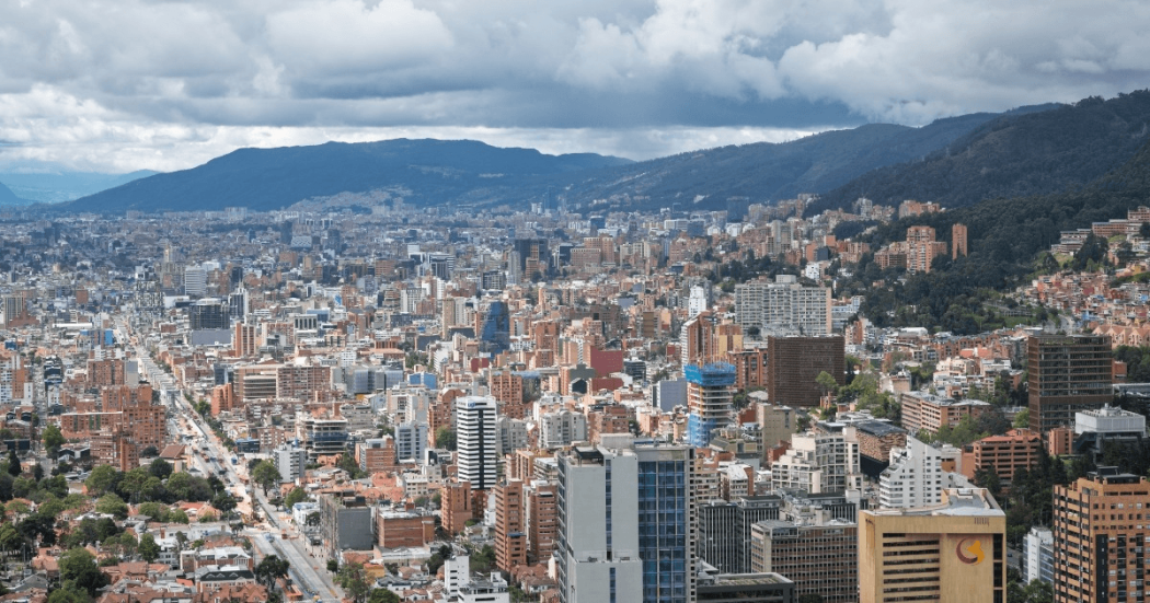 Vista panorámica de Bogotá con edificios residenciales y comerciales de diferentes alturas en primer plano.