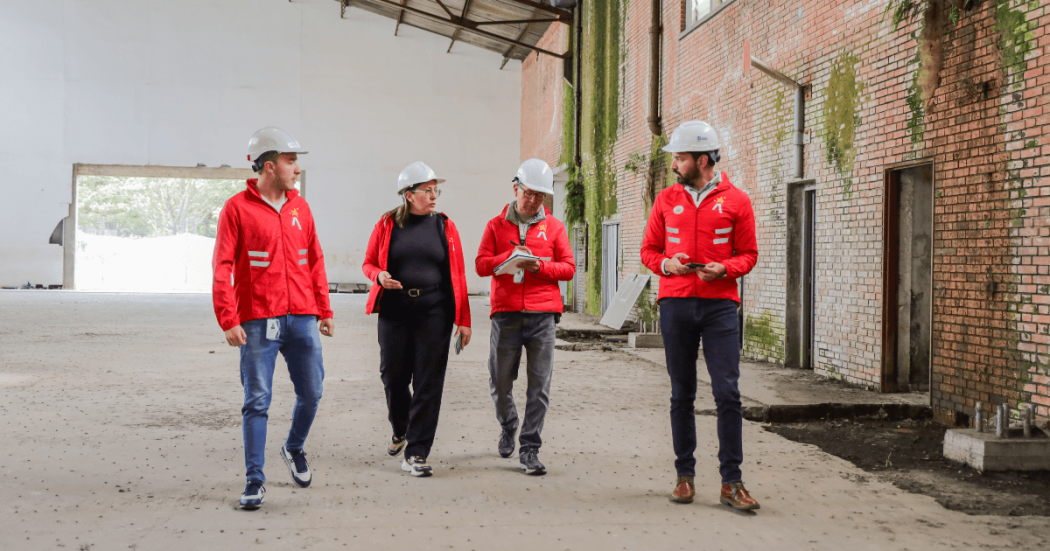 Funcionarios del IDRD con cascos de seguridad recorren una obra en construcción, donde se adelantan trabajos de recuperación de los coliseos menores de la Unidad Deportiva El Salitre.