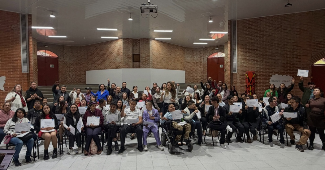Grupo de personas posando para la foto de grado del programa de formación, mostrando sus diplomas.