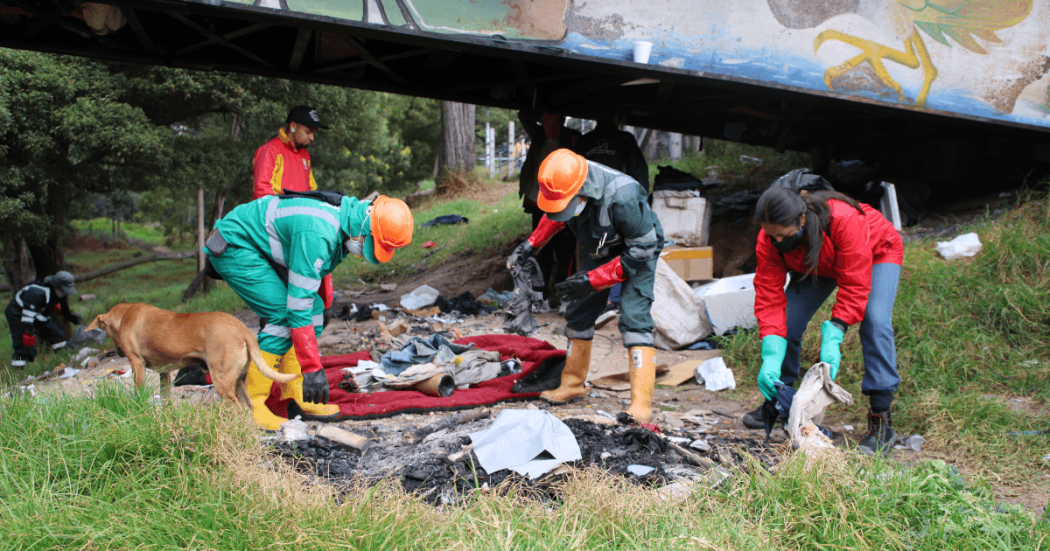 Personal operativo recoge residuos, textiles y otros elementos retirados de una ocupación informal bajo un puente, en una zona verde del humedal Tingua Azul.
