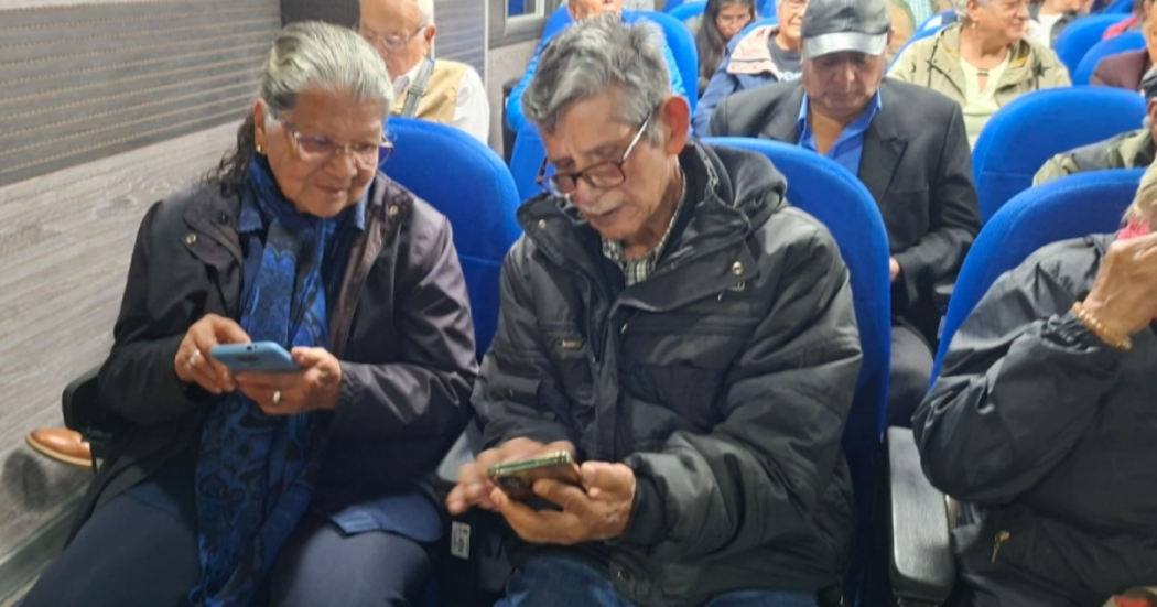 Foto de dos adultos mayores mirando la pantalla de sus celulares 