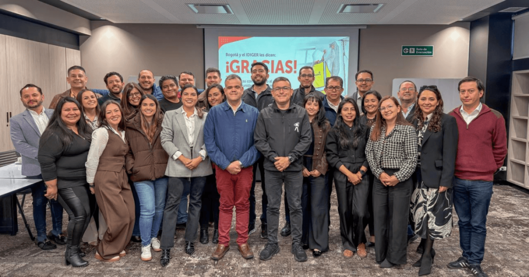 Grupo de profesionales posa para una fotografía en salón de reuniones tras misión de apoyo técnico a regiones afectadas por el sismo, con una pantalla al fondo que muestra el mensaje “¡GRACIAS!”