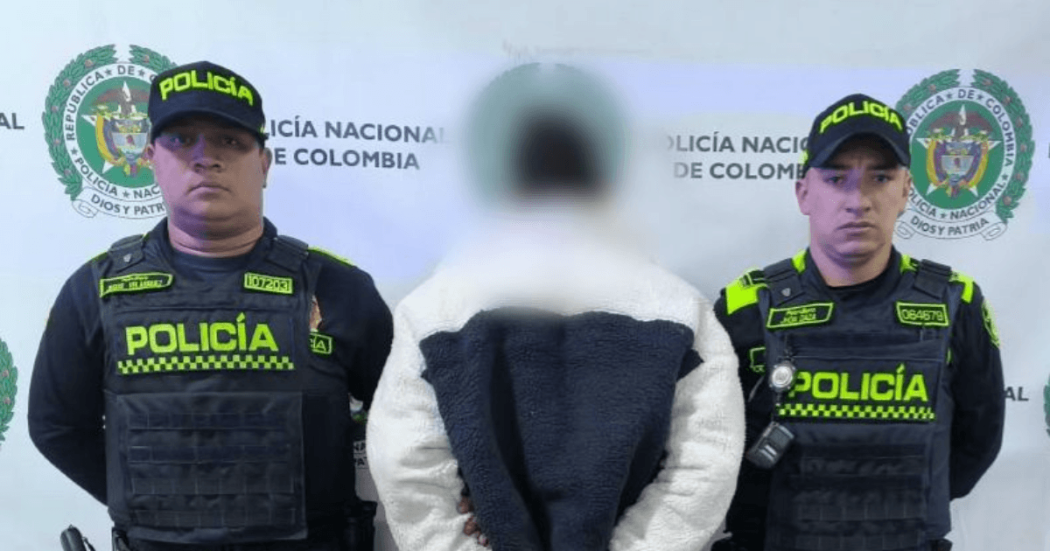 Hombre capturado, de espaldas, en medio de dos policías.