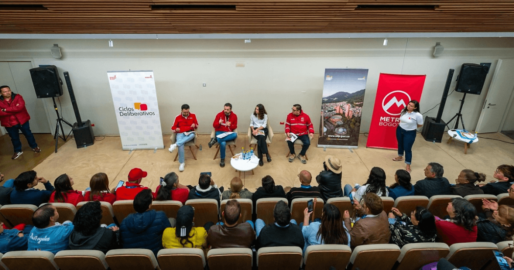 Funcionarios de la Alcaldía Mayor de Bogotá participando en un panel de debate frente a ciudadanos y participantes de un evento público.