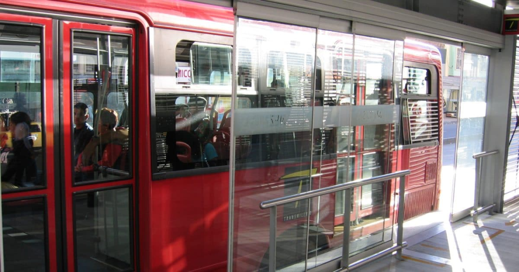 Foto de una estación de TransMilenio con un bus del Sistema al lado.