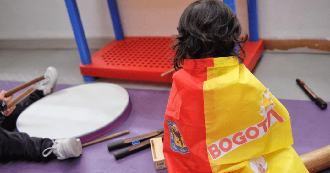 Foto que muestra un niño sentado con una bandera de Bogotá en la espalda
