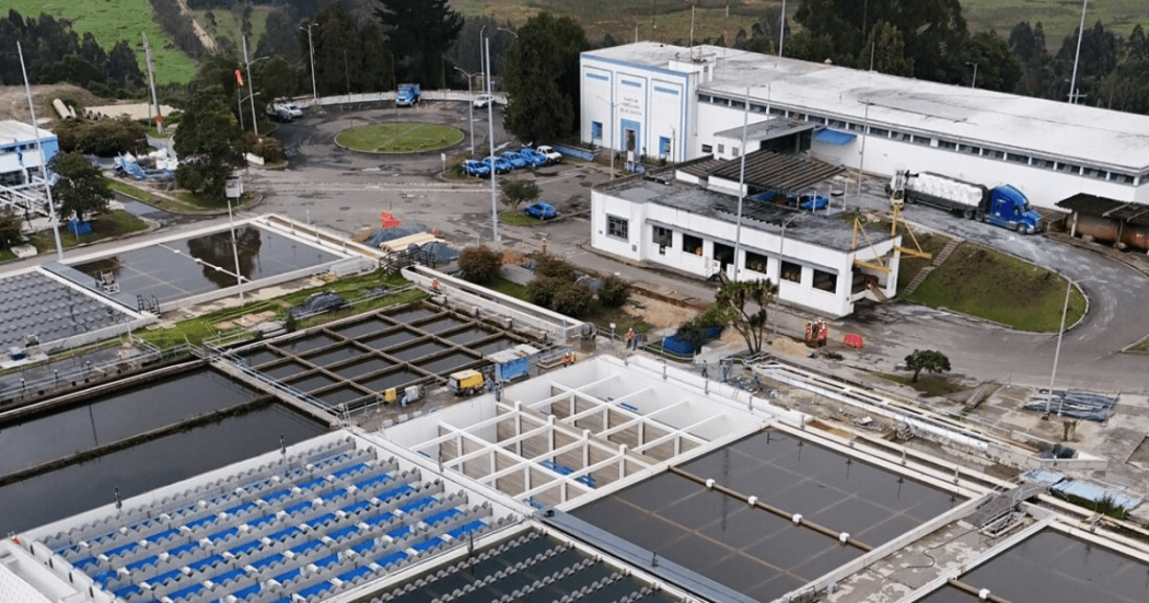 Foto que muestra una planta de tratamiento de aguas y edificios blancos en el fondo