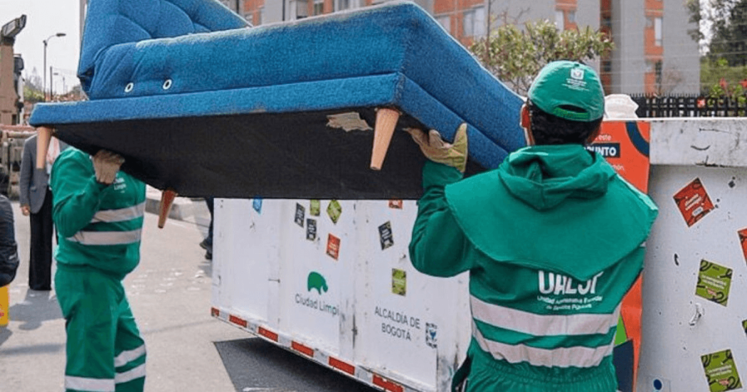 Foto que muestra dos personas dejando un mueble en un Ecopunto