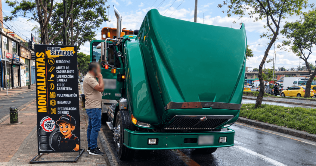Camión verde de carga estacionado al costado de una vía, con el capó levantado mientras una persona permanece junto al vehículo.