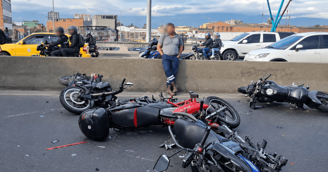 Motocicletas involucradas en un choque permanecen sobre la calzada de una vía principal de Bogotá. En el lugar se observan varias motocicletas caídas, fragmentos dispersos sobre el pavimento y vehículos circulando por los carriles contiguos.