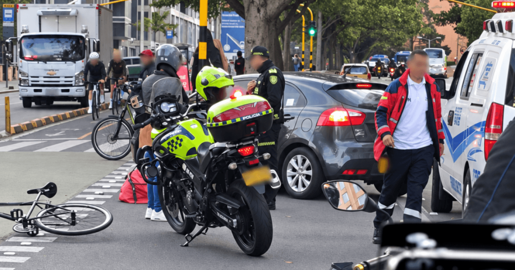 Accidente de tránsito en vía urbana con presencia de motocicleta policial, ambulancia, automóvil particular y bicicleta caída sobre la ciclorruta.