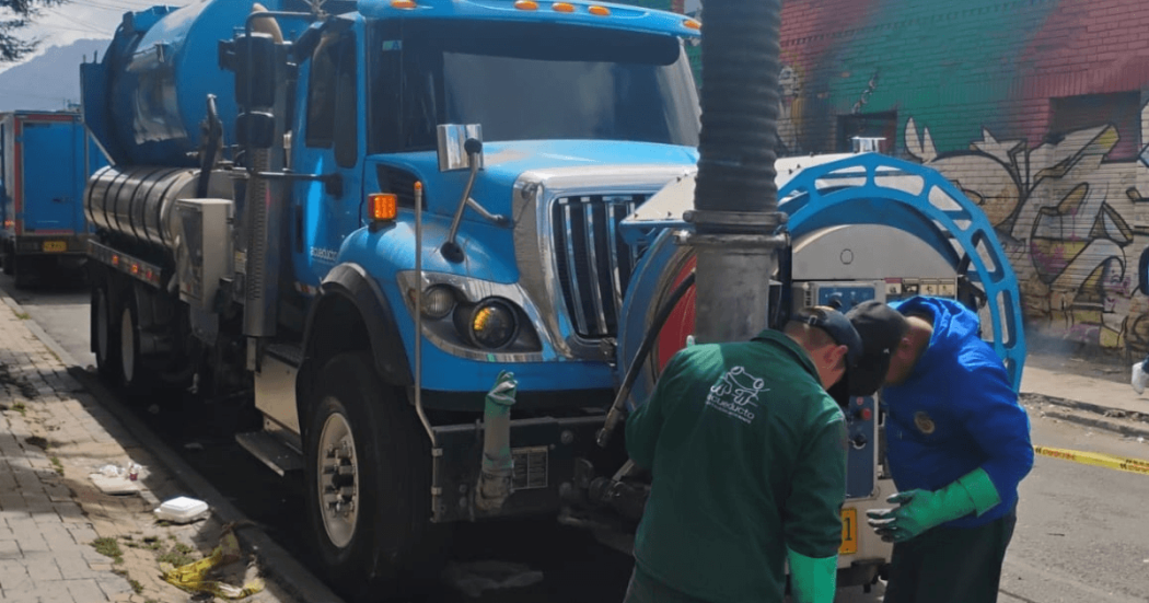 Foto que muestra personas con el uniforme del Acueducto de Bogotá junto a un carro vactor