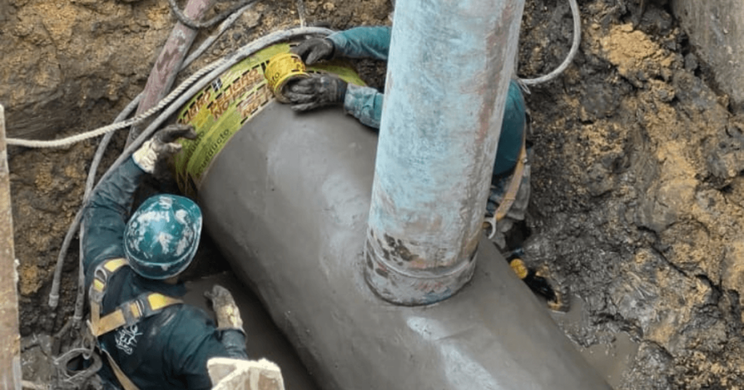 Foto que muestra dos personas del Acueducto de Bogotá reparando una tubería