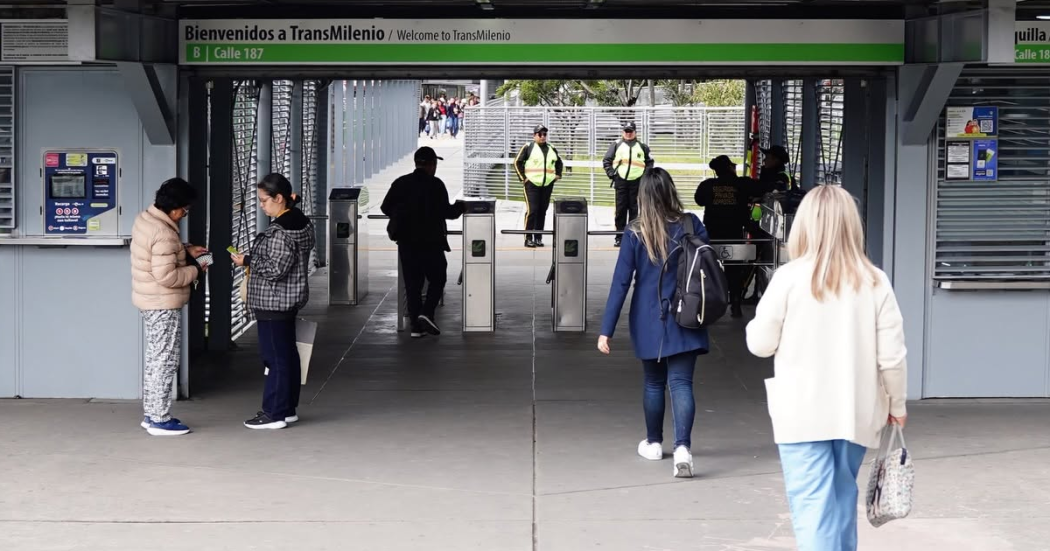 Foto de personas ingresando a una estación de TransMilenio usando su tarjeta para validar el pasaje.