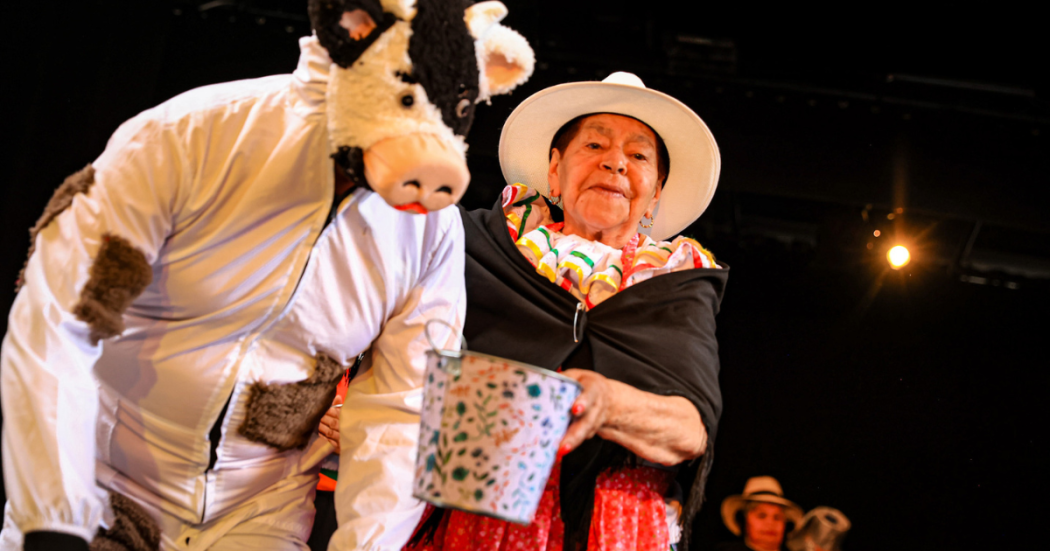 Imagen de mujer adulta mayor vestida con traje de Campesina y una persona disfrazada de vaca