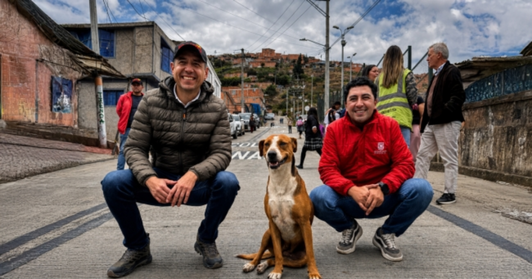 Foto de dos funcionarios con un perro cafe con blanco 