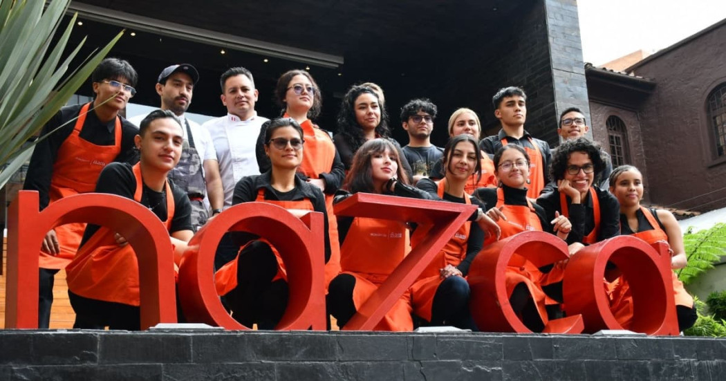Jóvenes estudiantes de gastronomía con el letrero del restaurante Nazca 