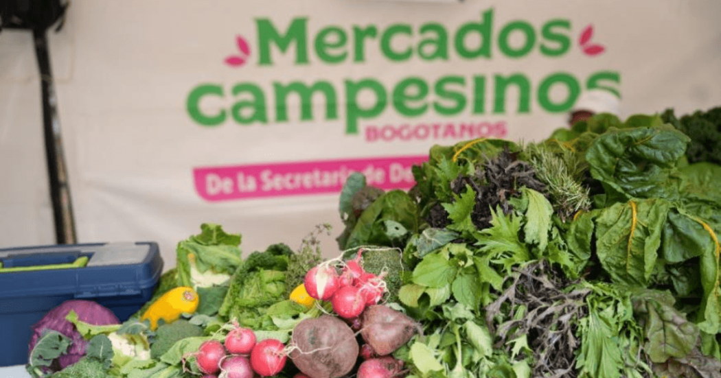 Productos agrícolas frescos, entre ellos rábanos, remolachas, lechugas y otras hortalizas, exhibidos en un puesto de Mercados Campesinos Bogotanos