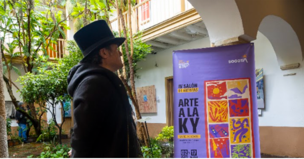 Imagen de un hombre vestido de mago observando en un cartel la información del Quinto Salón de Artistas a la KY 2026.
