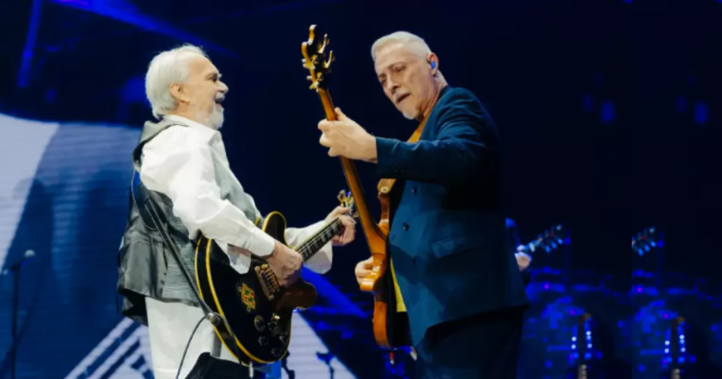 Imagen de dos hombres mayores tocan guitarra en un escenario.
