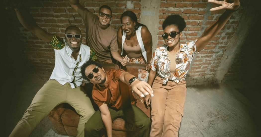 Imagen de 5 personas sonriendo sobre un sofá 