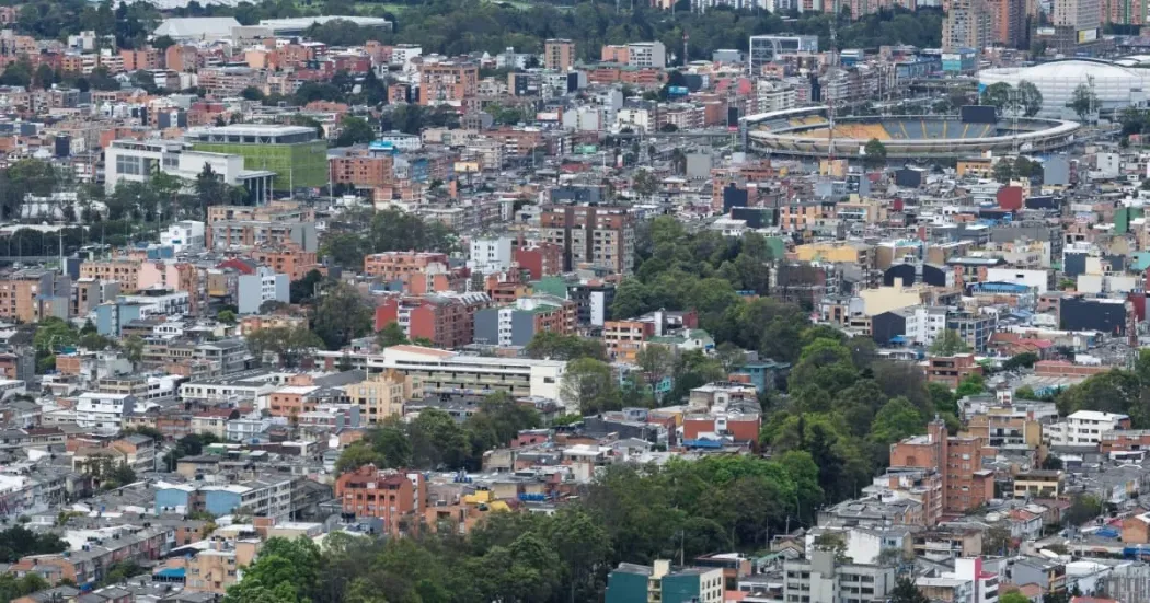 Vista panorámica de sectores residenciales y edificaciones de Bogotá, con viviendas de distintos tamaños distribuidas en una zona urbana rodeada de áreas verdes.