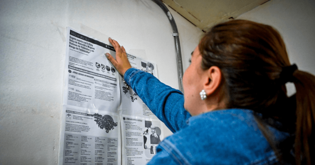 Mujer consultando un cartel con la ruta de atención a mujeres.
