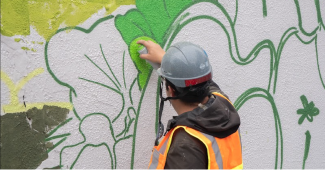 Imagen de un hombre dando la espalda que pinta un graffiti.