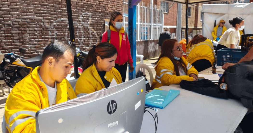 Foto que muestra hombres y mujeres trabajando frente a un computador