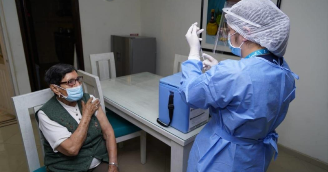 Imagen de una enfermera aplicando una vacuna a una mujer mayor que usa tapabocas