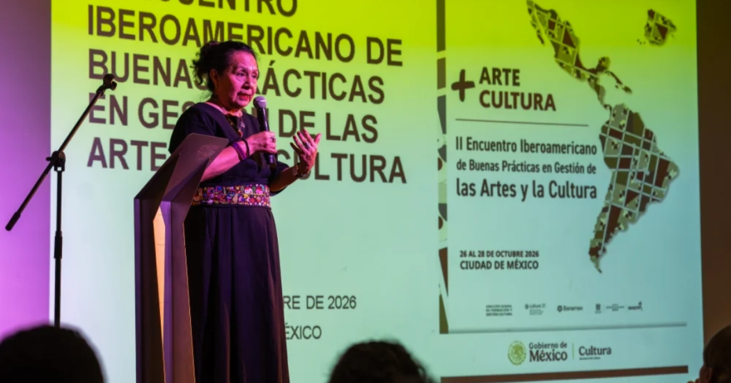 Imagen de una mujer hablando por un micrófono en una tarima