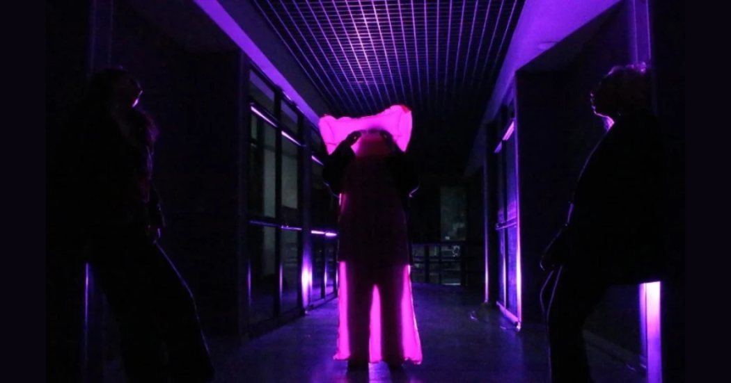 Imagen de tres personas en un corredor oscuro.