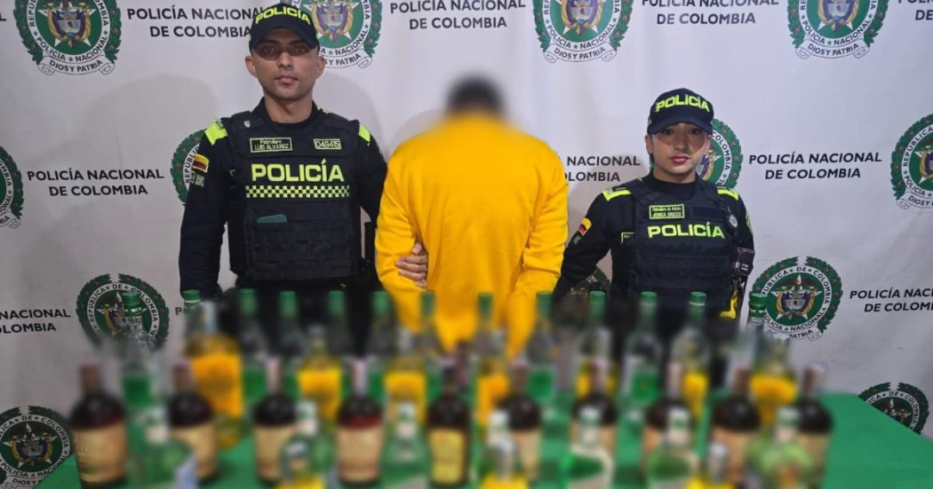 Foto el hombre captutado con las botellas de licor adulterado junto a uniformados de la Policía de Bogotá.