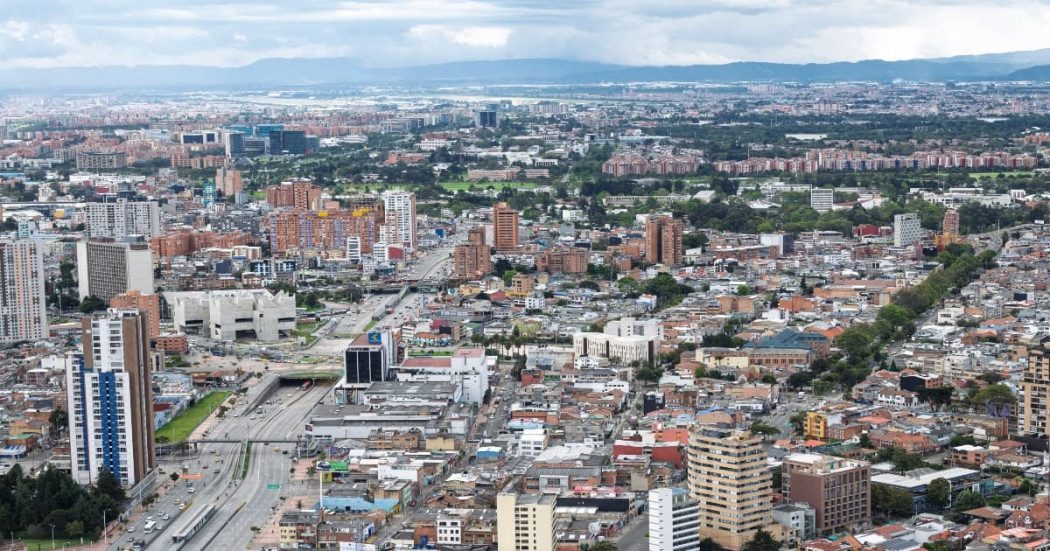 Vista panorámica de Bogotá con edificaciones de diferentes alturas, vías principales y zonas densamente urbanizadas para referenciar el pronóstico del tiempo y estado del clima.