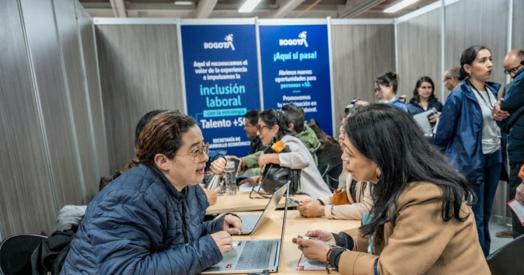 Ciudadana en una feria de empleo en Bogotá junto a una funcionaria de la Secretaría Distrital del Desarrollo Económico